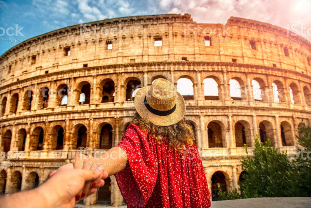 Romantic woman and man holding hands and walking to Colosseum Rome, Italy.